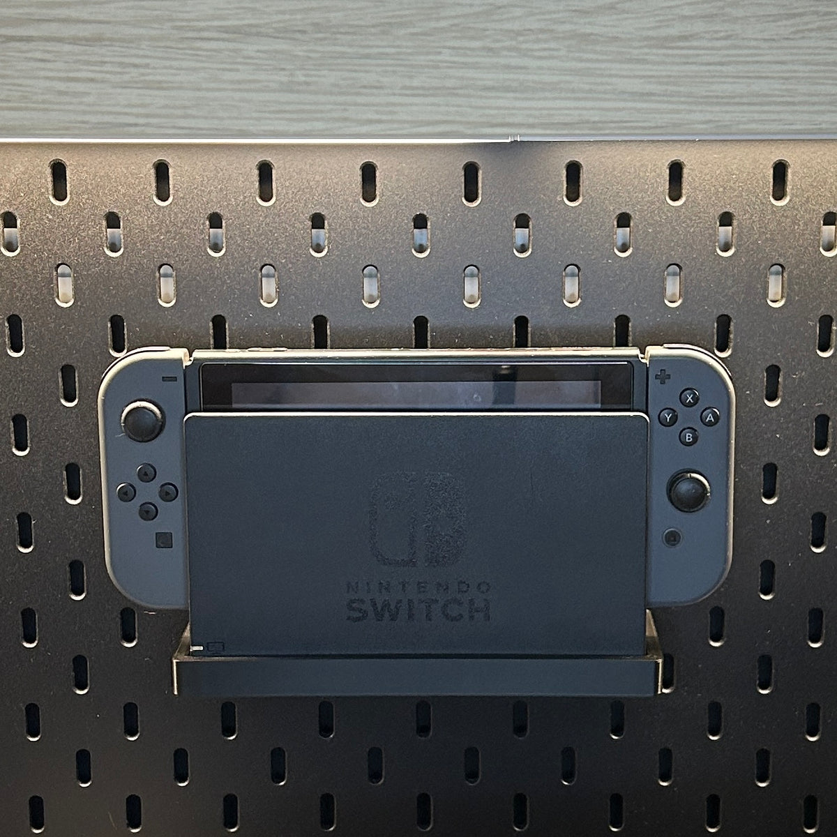 Nintendo Switch rangée sur son support fixé au panneau IKEA SKÅDIS noir