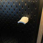 Support casque blanc clipsé seul sur un panneau IKEA SKÅDIS noir