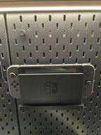 Cache fixation noir clipsé sur un panneau SKÅDIS, support Nintendo Switch en dessous